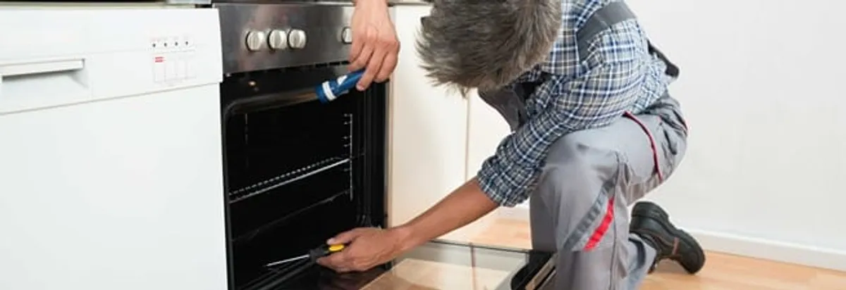 Oven repair technician inspecting and servicing an electric oven in Jackson, MS