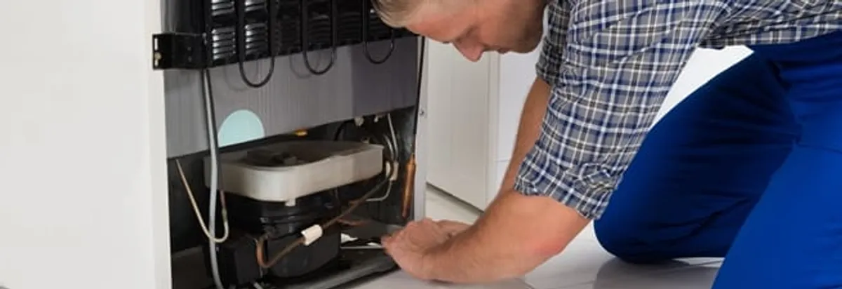 Refrigerator repair technician servicing the compressor and condenser area in Jackson, MS