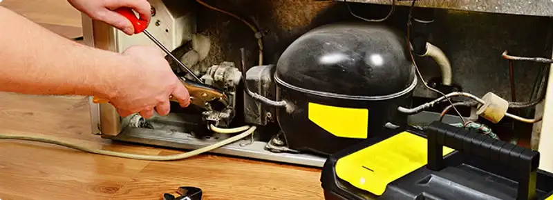 Refrigerator repair technician fixing the compressor and wiring in Jackson, MS